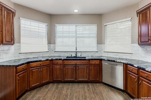 kitchen featuring dark stone countertops, dark wood-style flooring, a sink, decorative backsplash, and dishwasher