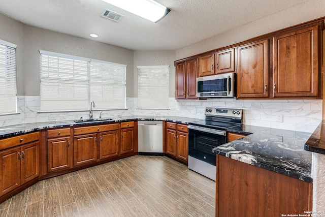 kitchen featuring visible vents, light wood-style flooring, a sink, appliances with stainless steel finishes, and brown cabinets