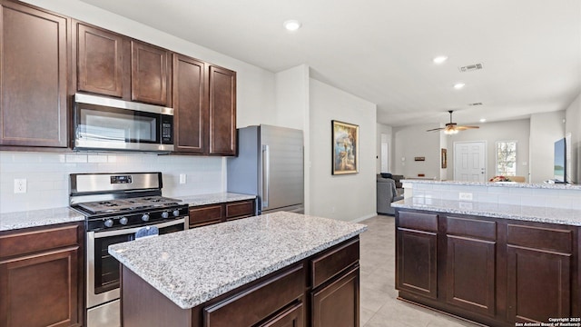 kitchen with visible vents, dark brown cabinets, decorative backsplash, stainless steel appliances, and a ceiling fan