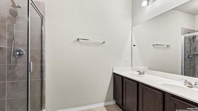 bathroom featuring a sink, tile patterned floors, double vanity, and a tile shower