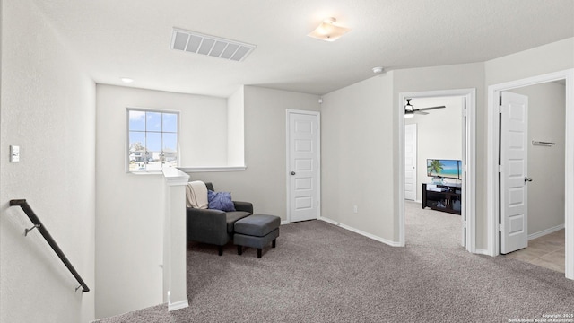 sitting room featuring visible vents, an upstairs landing, a ceiling fan, carpet flooring, and baseboards