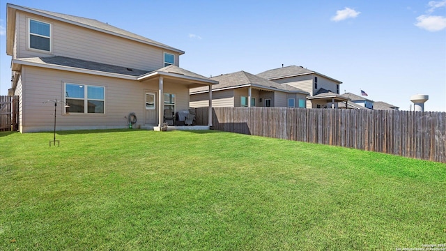 rear view of property featuring a lawn and a fenced backyard