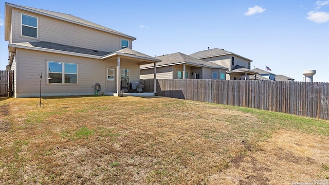 rear view of property featuring a yard and a fenced backyard