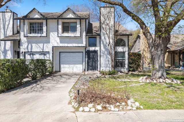 tudor home featuring roof with shingles, stucco siding, a chimney, a garage, and driveway