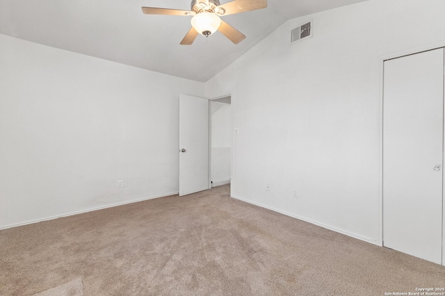 carpeted empty room featuring visible vents, a ceiling fan, and vaulted ceiling