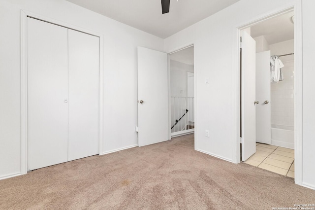 unfurnished bedroom with a closet, carpet, ensuite bath, and a ceiling fan