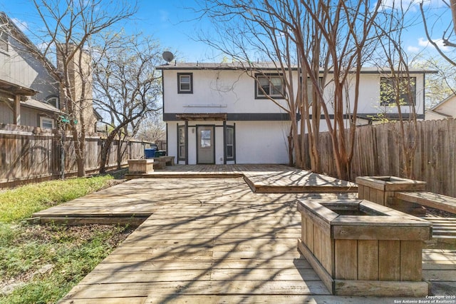 rear view of property with a deck, a fenced backyard, and stucco siding