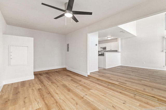 unfurnished living room featuring electric panel, baseboards, light wood-style floors, and ceiling fan