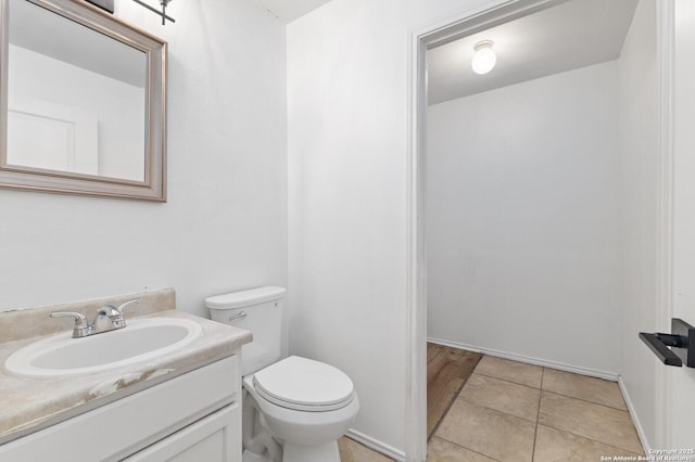 half bathroom featuring vanity, tile patterned floors, and toilet