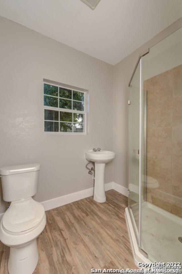 full bathroom featuring baseboards, toilet, wood finished floors, and a shower stall