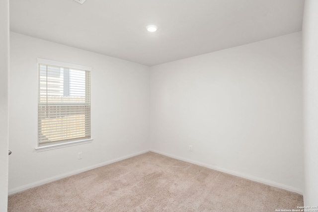 unfurnished room featuring light carpet and baseboards