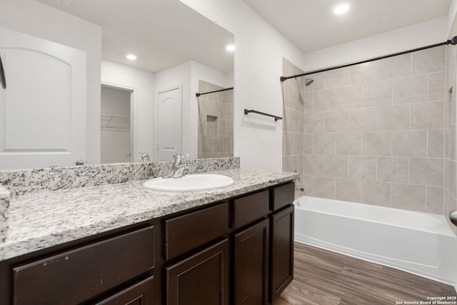 bathroom with recessed lighting, shower / bath combination, wood finished floors, and vanity