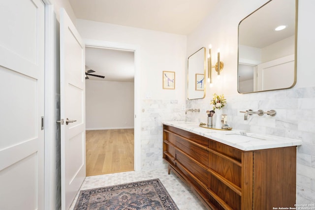 bathroom with double vanity, a wainscoted wall, tile walls, and a sink