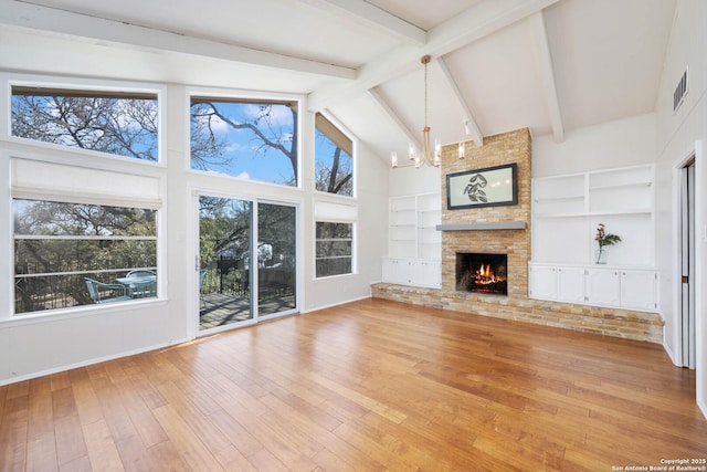 unfurnished living room featuring built in shelves, high vaulted ceiling, beam ceiling, light wood finished floors, and a chandelier