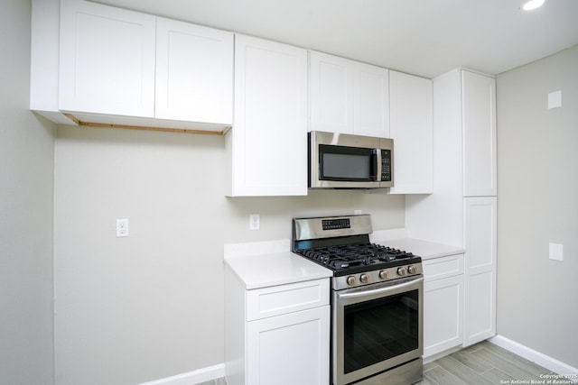 kitchen with light countertops, white cabinets, baseboards, and appliances with stainless steel finishes