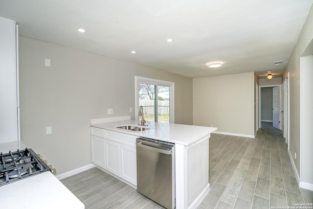 kitchen featuring wood tiled floor, a peninsula, a sink, light countertops, and dishwasher