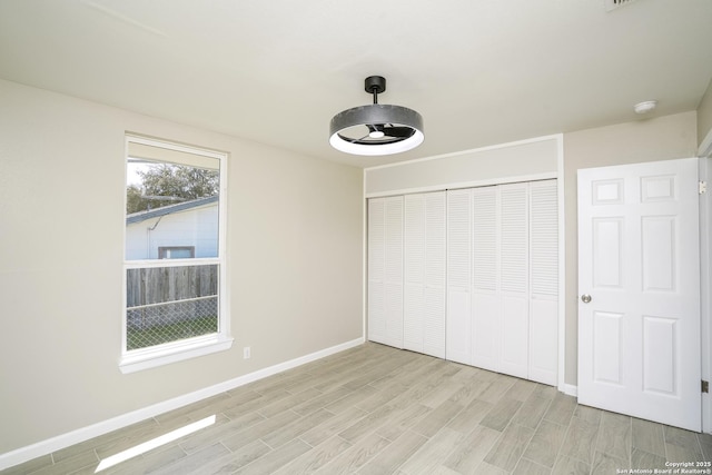 unfurnished bedroom featuring baseboards, a closet, and wood finish floors