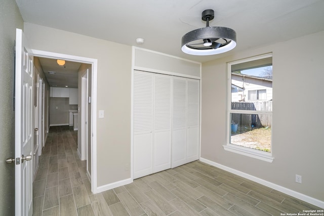 unfurnished bedroom featuring a closet, baseboards, and wood finish floors