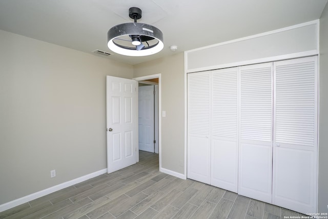 unfurnished bedroom with baseboards, visible vents, a closet, and wood finish floors