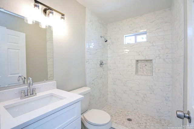 full bath featuring tiled shower, toilet, and vanity