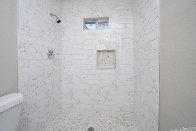 full bath with tiled shower and toilet