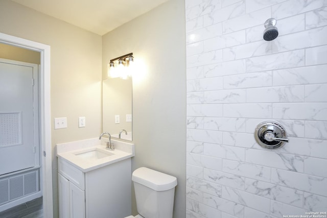 full bath with visible vents, toilet, tiled shower, and vanity