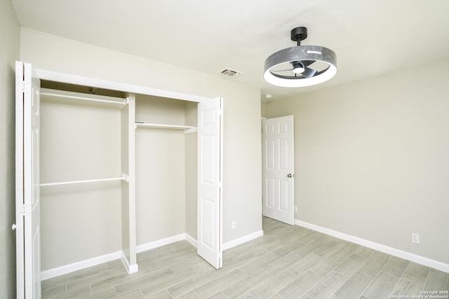 unfurnished bedroom with baseboards, visible vents, a closet, and wood finish floors