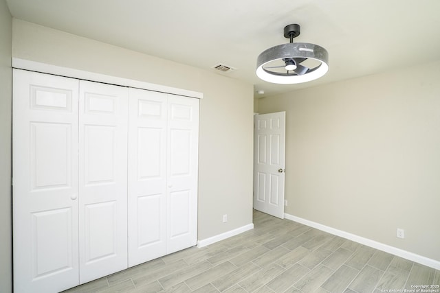 unfurnished bedroom with a closet, visible vents, baseboards, and wood tiled floor