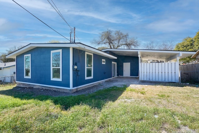 exterior space featuring driveway, a carport, a front lawn, and fence