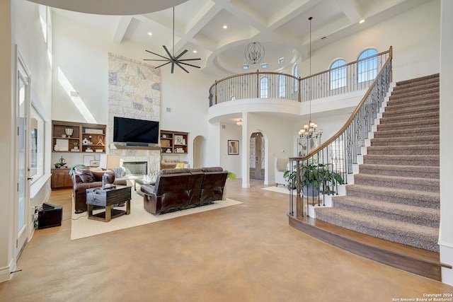 living room with finished concrete flooring, arched walkways, stairs, a stone fireplace, and a chandelier