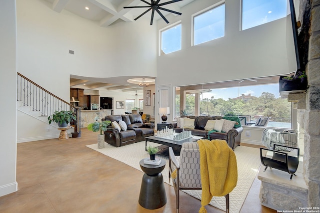 living room featuring beam ceiling, plenty of natural light, a ceiling fan, and baseboards