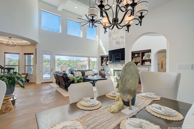 dining space with an inviting chandelier, beam ceiling, recessed lighting, arched walkways, and a glass covered fireplace