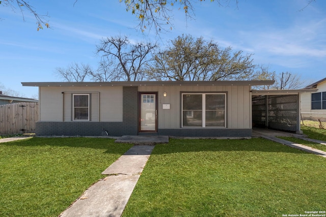 view of front of property featuring board and batten siding, a front lawn, fence, and brick siding