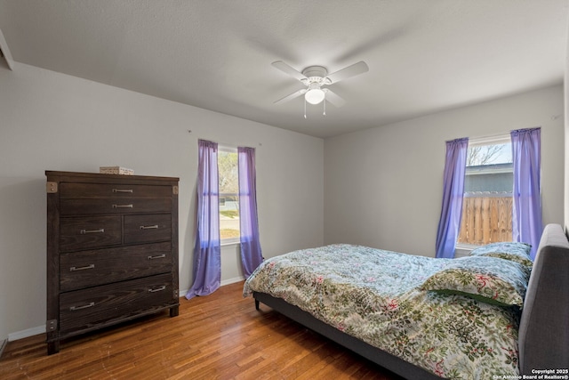 bedroom featuring baseboards, multiple windows, and wood finished floors