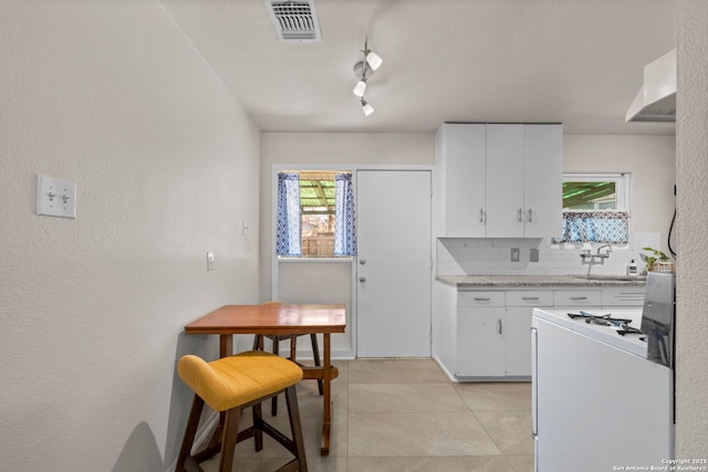 kitchen featuring visible vents, a sink, decorative backsplash, white cabinets, and range