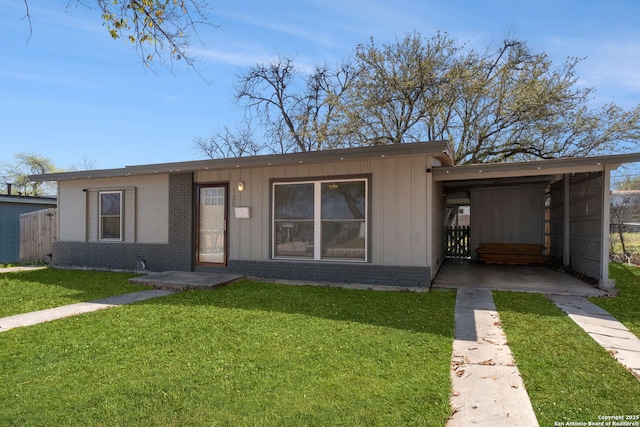 view of front of home featuring brick siding, driveway, a front yard, and a carport