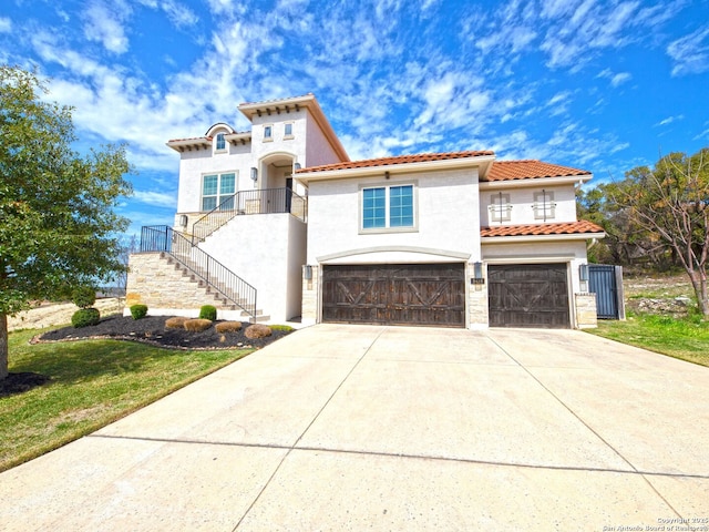 mediterranean / spanish-style house with a tiled roof, concrete driveway, stairs, stucco siding, and an attached garage