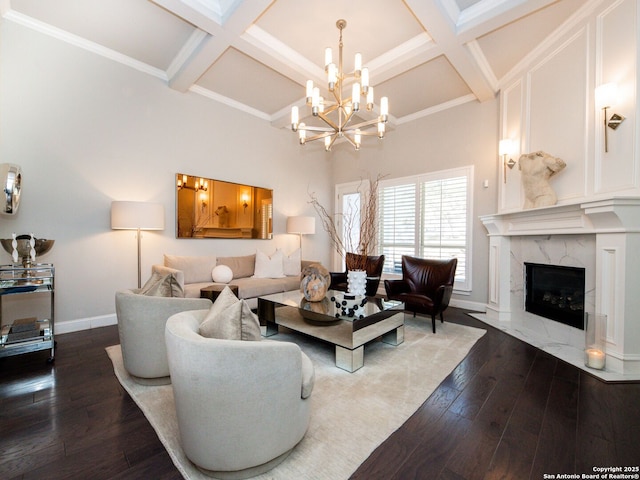 living room featuring a chandelier, coffered ceiling, baseboards, and hardwood / wood-style floors