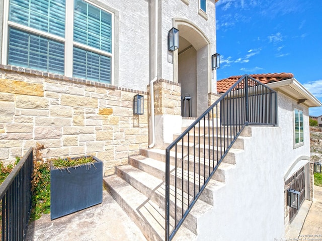 view of exterior entry featuring stone siding and stucco siding