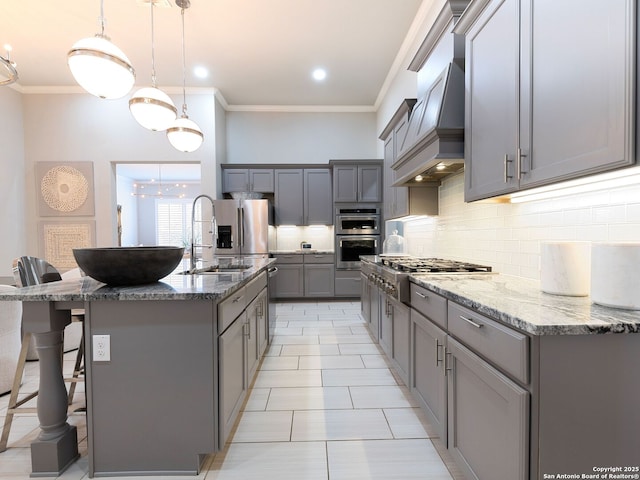 kitchen with custom range hood, decorative backsplash, gray cabinets, stainless steel appliances, and a sink