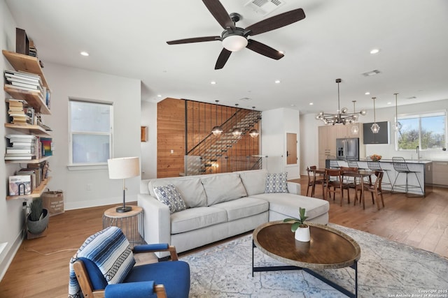 living area with recessed lighting, visible vents, light wood-style flooring, and ceiling fan with notable chandelier