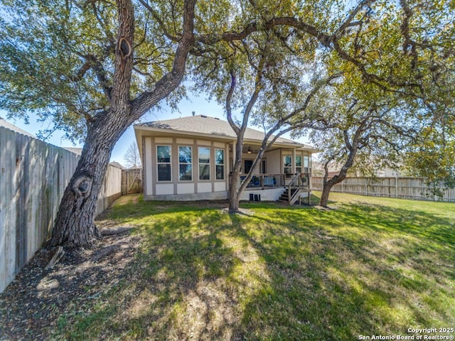 back of property with a yard, a fenced backyard, and ceiling fan