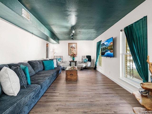 living area featuring visible vents, rail lighting, baseboards, and wood finished floors