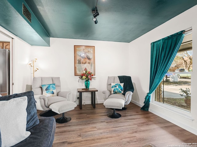 sitting room featuring track lighting, wood finished floors, visible vents, and baseboards