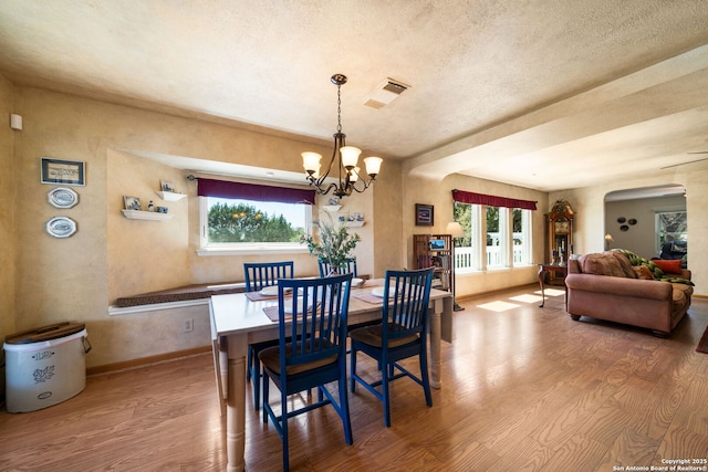 dining area with an inviting chandelier, wood finished floors, visible vents, and arched walkways