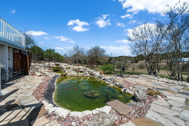 view of yard with a garden pond and a patio area