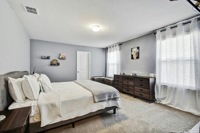 bedroom with carpet, visible vents, and a textured ceiling