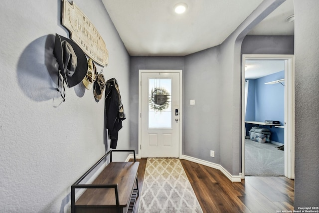 entryway with baseboards, arched walkways, and wood finished floors