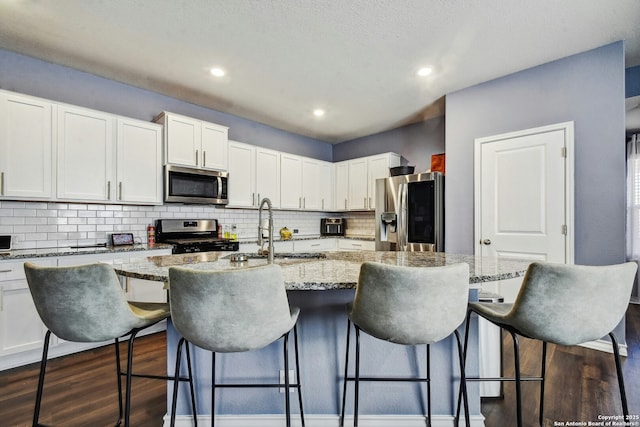 kitchen featuring decorative backsplash, a sink, dark wood-style floors, and stainless steel appliances