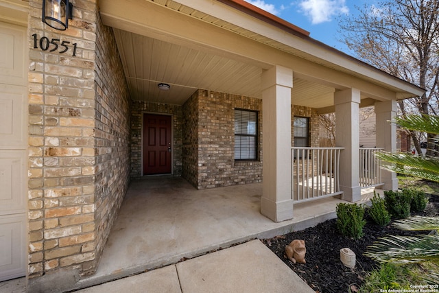 property entrance with brick siding and covered porch